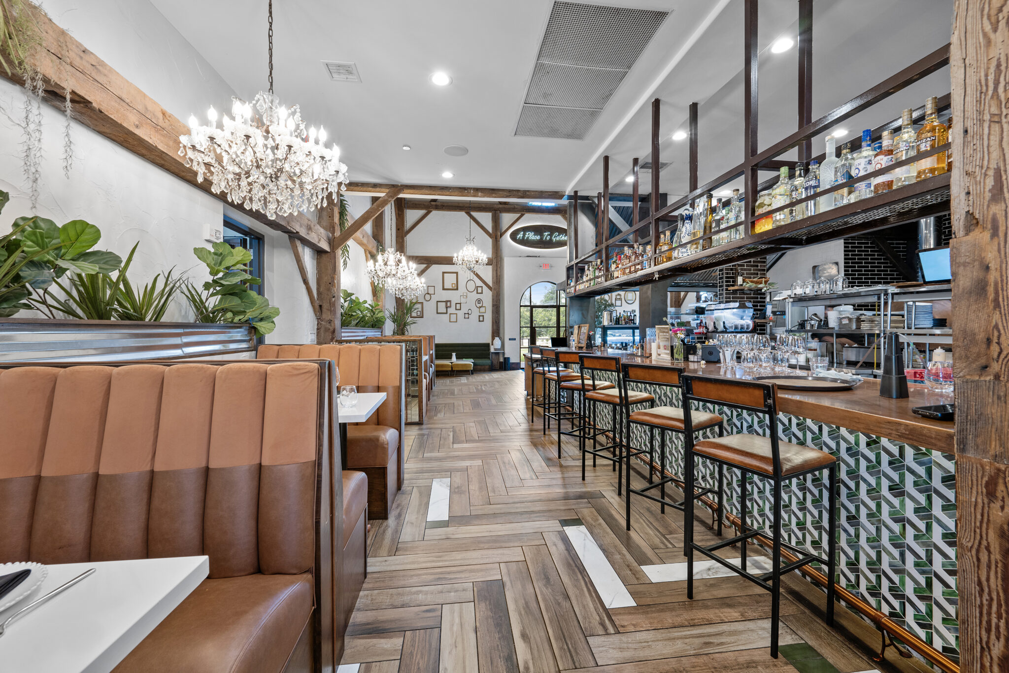 Commercial photography of an upscale restaurant interior with bar seating, chandeliers, and wood accents