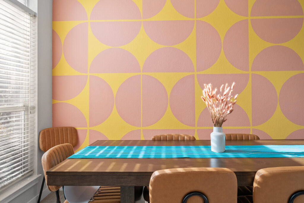 Professional real estate photography of a modern dining room featuring designer wallpaper, natural light, and contemporary furnishings