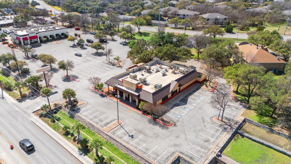 Austin commercial real estate photographer capturing an aerial drone view of a shopping center with surrounding businesses, parking, and professional commercial photography.