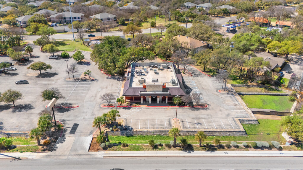 Austin commercial real estate photographer capturing a drone aerial front view of a commercial property with parking lot and surrounding business area.