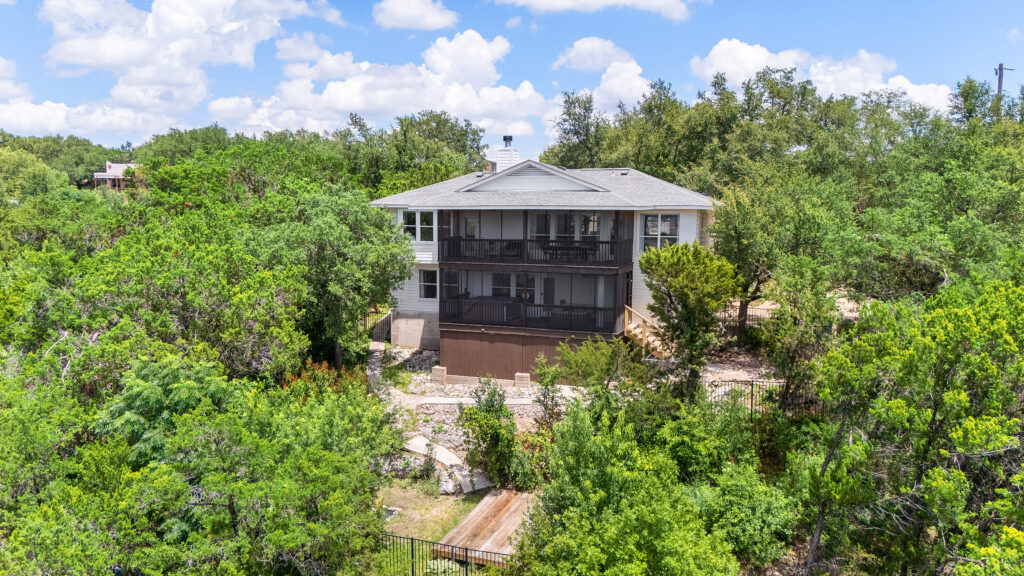 Lago Vista real estate photography featuring a drone aerial view of a luxury home's backyard and rear exterior overlooking the Texas Hill Country.