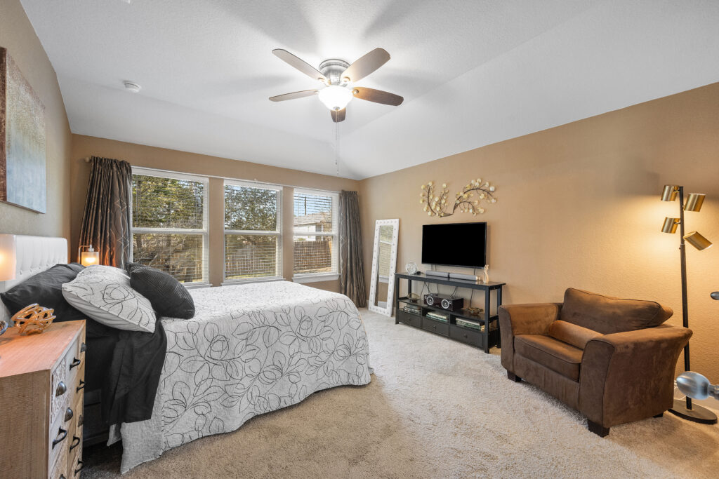 Lago Vista real estate photography featuring a luxury primary bedroom with panoramic Hill Country views, abundant natural light, and professional interior photography.